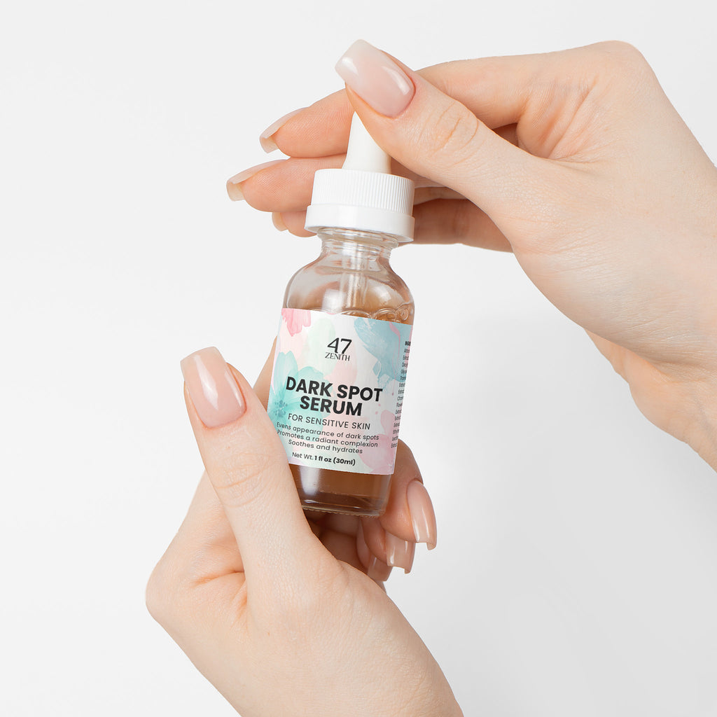 Bottle of dark spot serum held by a hand on a light background