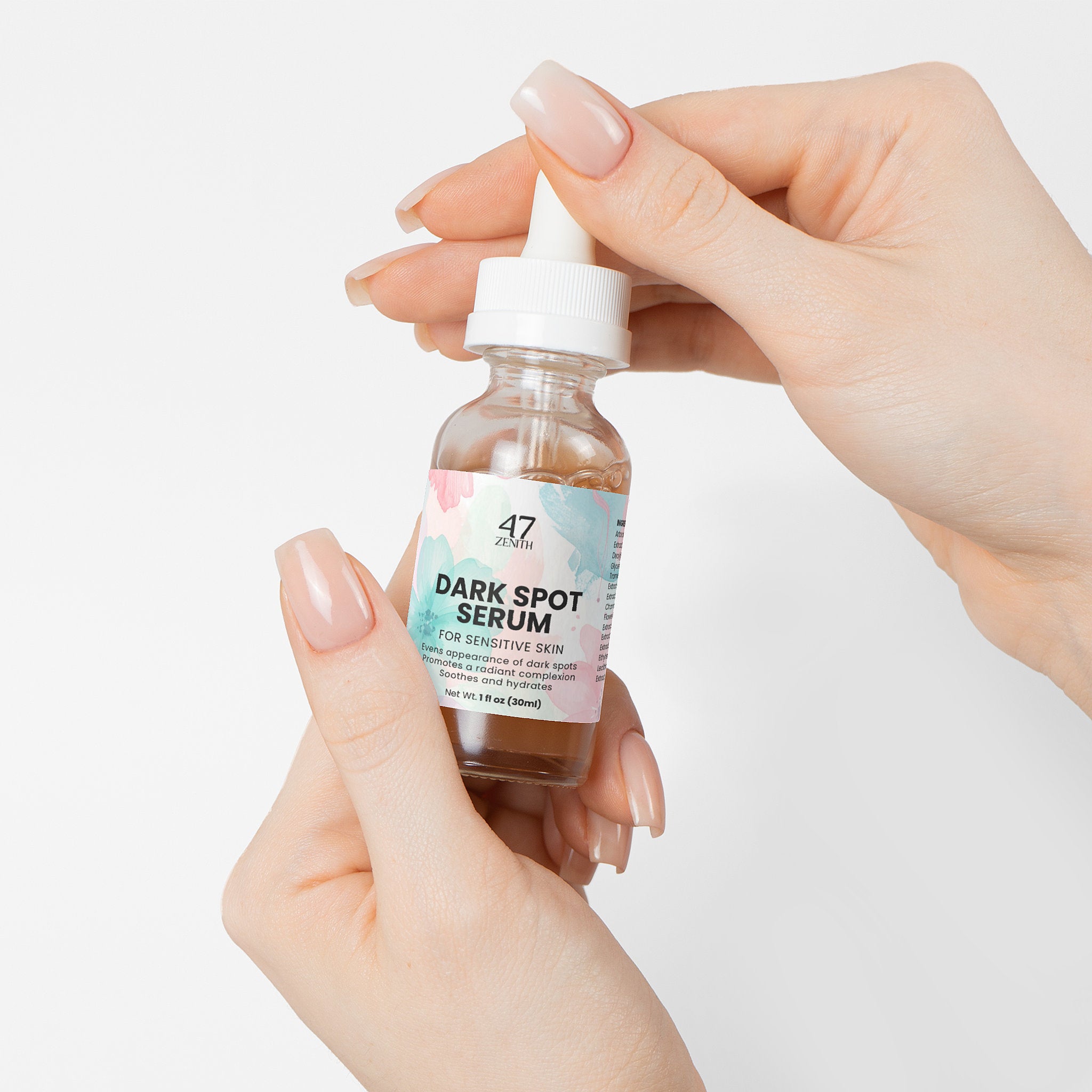 Bottle of dark spot serum held by a hand on a light background